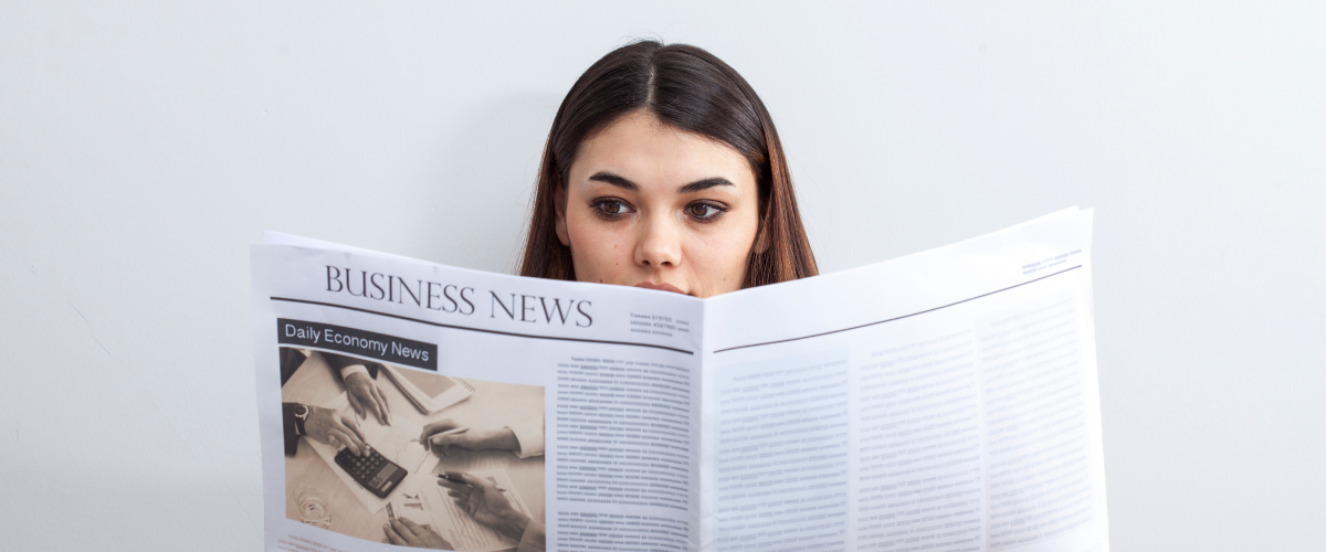 An image of a woman reading a business, financial and fintech newspaper