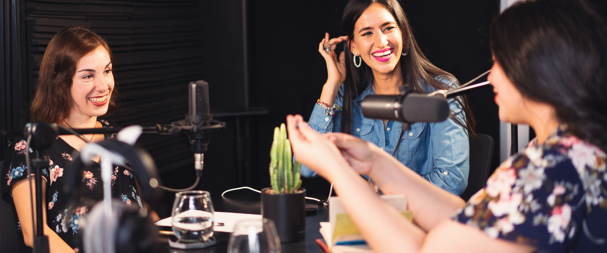 A group of three women in a podcast environment with microphones.