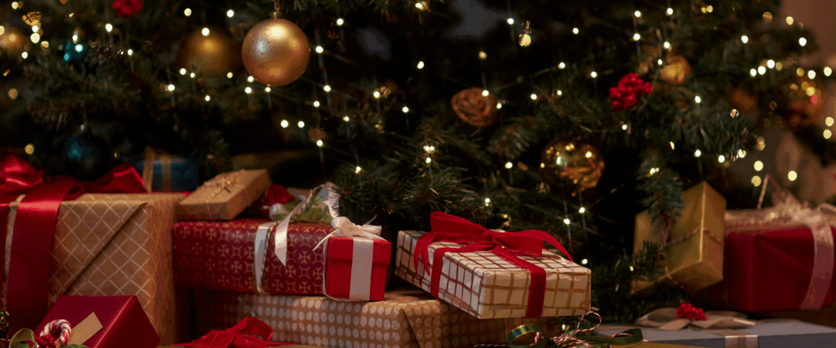 An image of a festive Christmas tree with wrapped presents underneath