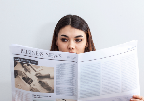 An image of a woman reading a business, financial and fintech newspaper